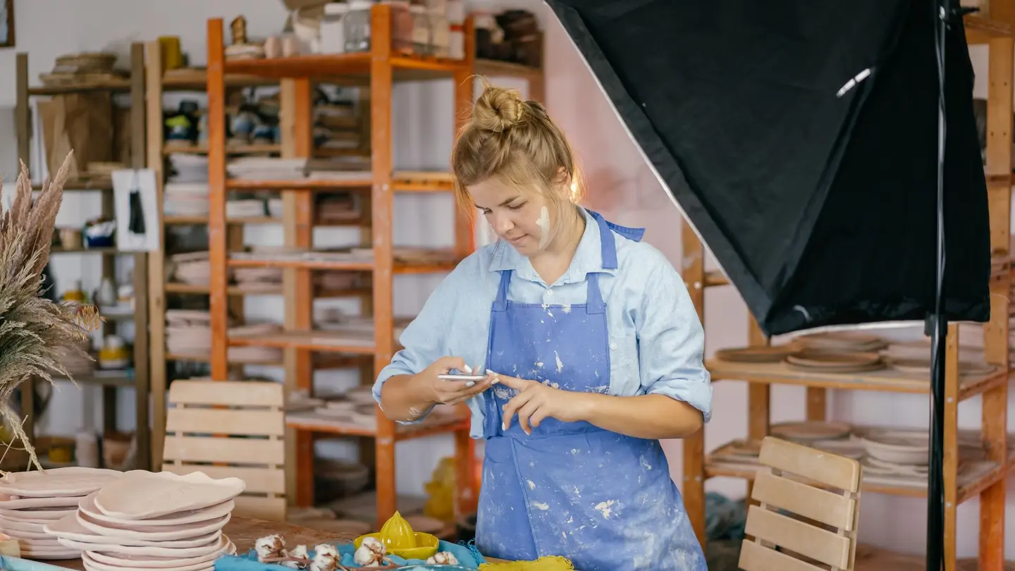 Una artesana en su taller junto a sus piezas terminadas